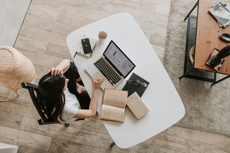 Freelancer multitasking efficiently with a laptop, planner, and coffee, managing multiple projects productively.