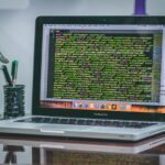 Laptop displaying code on screen at a developer's desk with a robot figurine and pen holder
