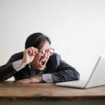 Frustrated man in glasses yelling at his laptop while working