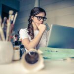 Woman concentrating on laptop while solving a coding problem at her desk